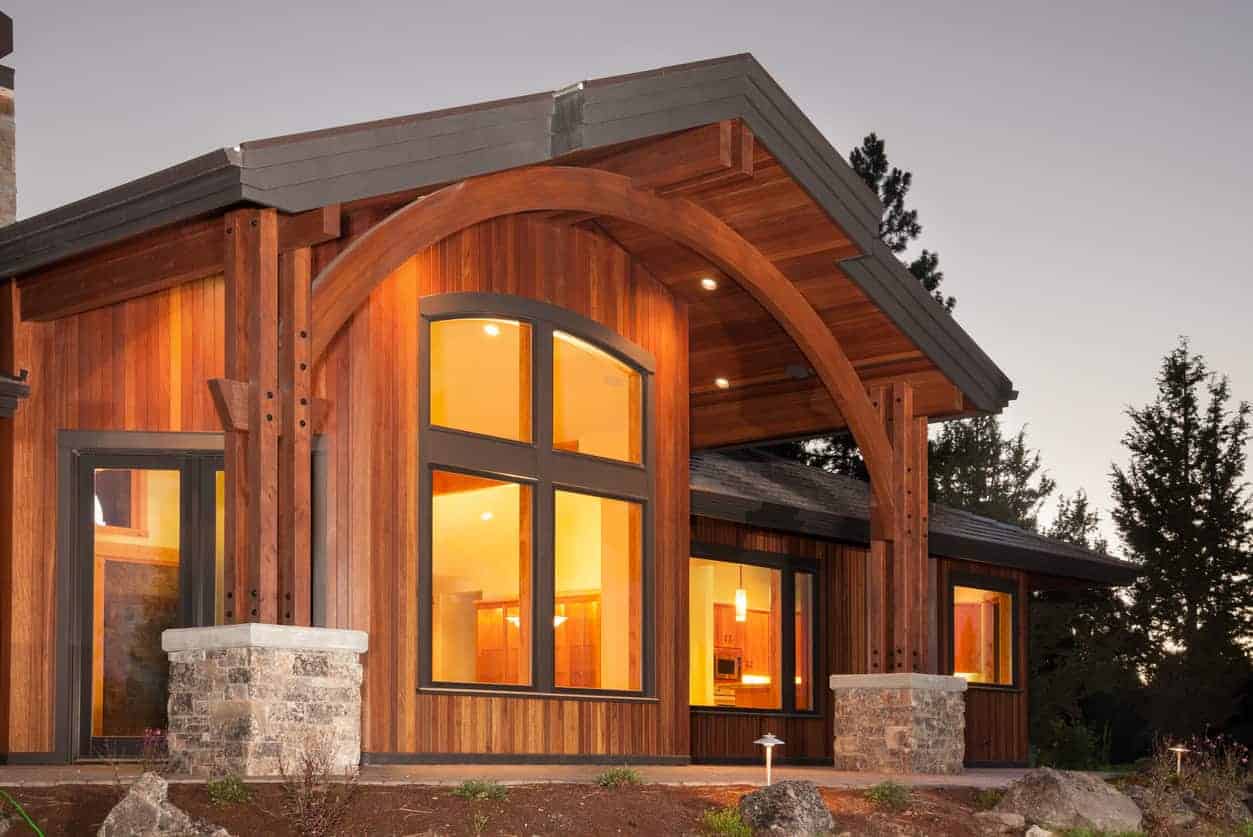 一个新房子的特写，垂直木板住宅外观，包括相同的木材支撑柱。对比是用深灰色的装饰。虽然有很多木材(丰富的红色木材)，但它是有效的。