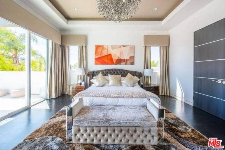 一个主要的卧室，一个豪华的床由一个迷人的吊灯设置在令人惊叹的托盘天花板。