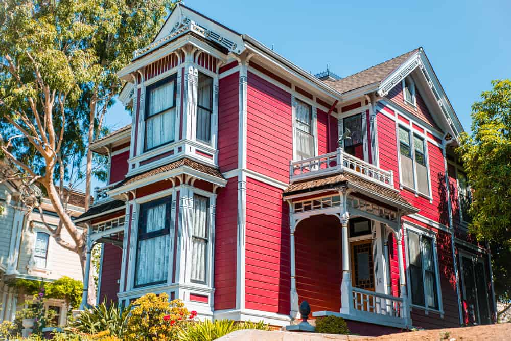 明亮的红色维多利亚风格的房子，两层都有大而突出的前窗。