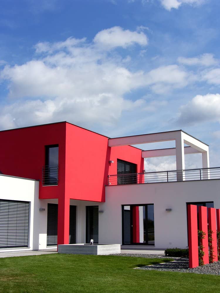 红色和白色外观的现代住宅。这个吸引人的立方体风格的家包括屋顶阳台和前院的红色雕塑栅栏。