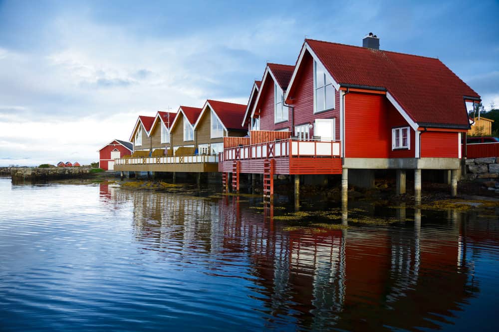 红色的房子架空在水面上。这些房屋采用旧设计，但都是新的，有漂亮的落地窗和伸出水面的现代甲板栏杆。