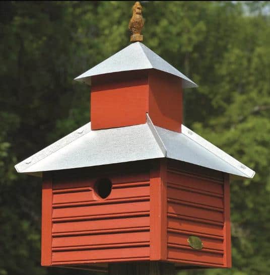 一个红橙色的鸟屋，有优质的白色屋顶。