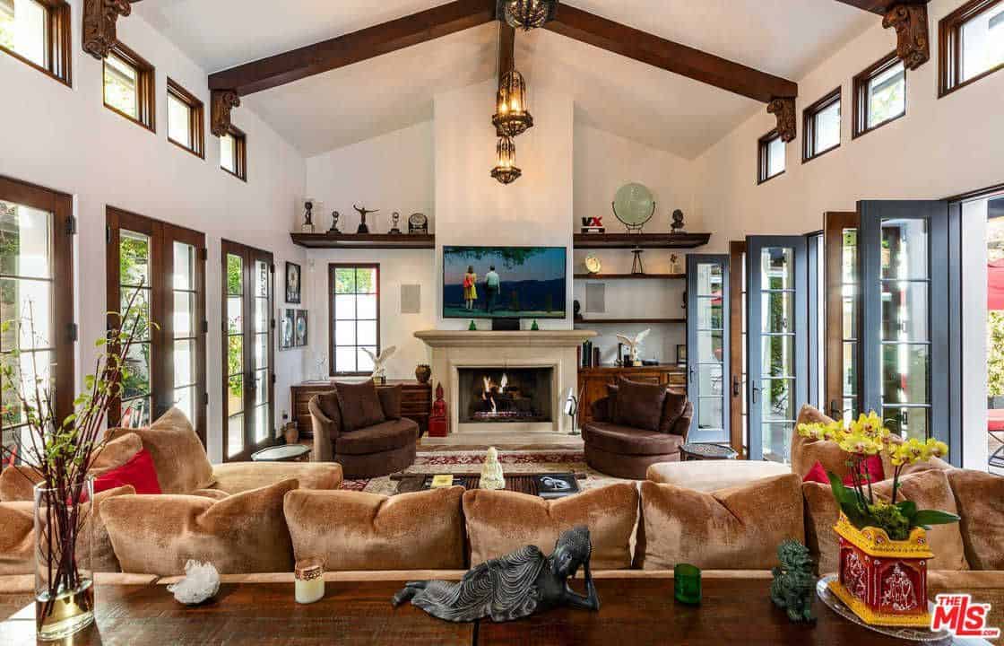 茶色天鹅绒枕头放在u形沙发上，面对着电视和壁炉，两边是棕色的拥抱椅。