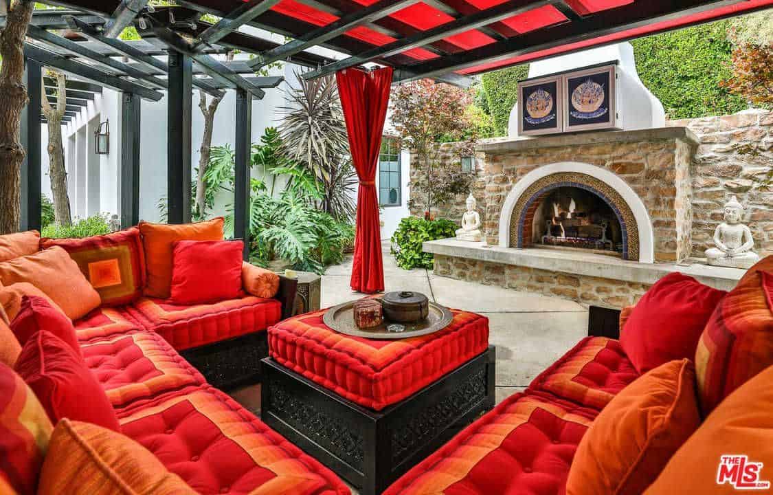 这个优雅的露台提供红色主题的座椅，桌子和窗帘。房间前面有个壁炉。
