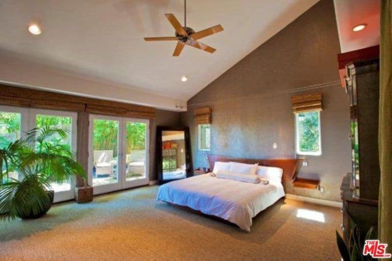 卧室拥有全地毯地板和一张大号床，以及棚顶上的嵌入式灯。还有一扇门通向房子的室外。