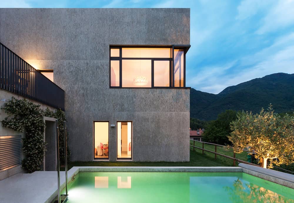 方形现代住宅，混凝土外观，可以看到山和小后院游泳池。