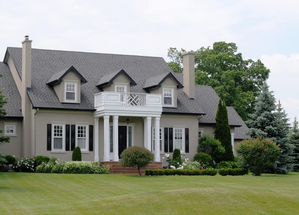 大房子，灰色的外观和巨大的前院花园，拥有美丽的植物，树木和维护良好的草坪。
