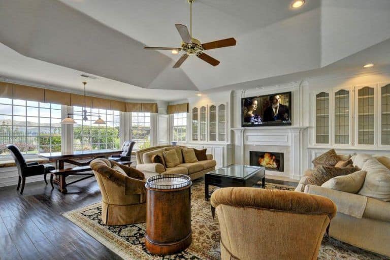 开放式的客厅里摆放着棕褐色的分体椅和圆形靠背椅，正对着现代化壁炉上方的电视。