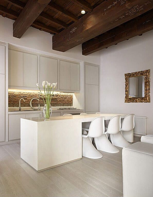 全白色的厨房充满了极简的木岛和餐桌混合。上面的大型天然木梁增加了对比。