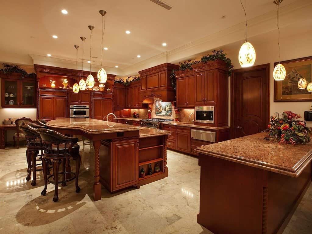 整个厨房的米色大理石地板上铺着丰富的红色木材。大型两层岛与大理石台面功能餐厅座位和内置存储。