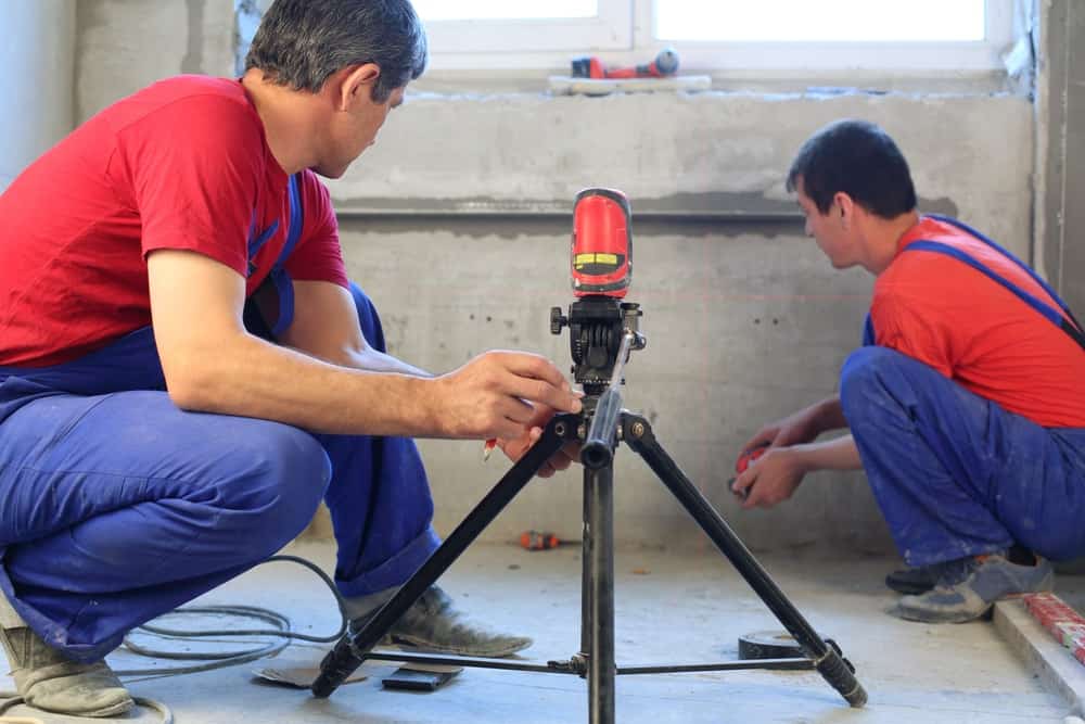 两名建筑工人正在使用激光水平仪来确定水泥应用的适用性。