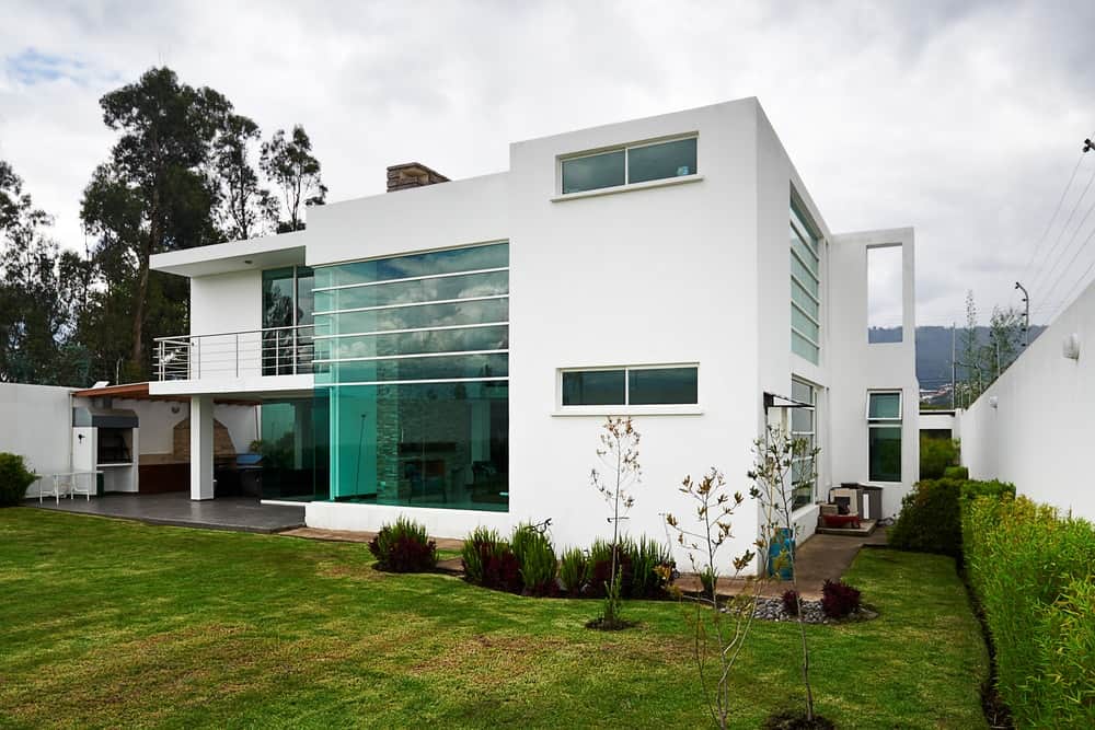 现代化的房子，有玻璃窗，绿色的后院，平屋顶。