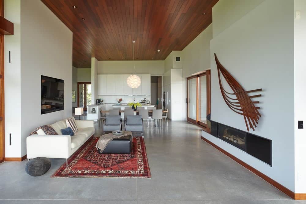 现代的客厅，白色的墙壁，硬木天花板和灰色的成品地板，上面有一个优雅的地毯。