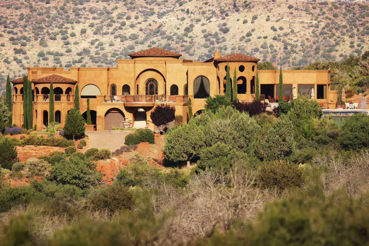 巨大的豪华灰泥住宅，设有地理窗户，隐藏在被绿色植物包围的沙漠景观中。