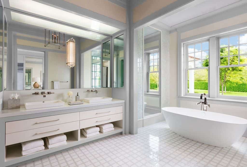 宽敞的当代浅灰色和白色浴室，白色的独立浴缸可以俯瞰广阔的地面。