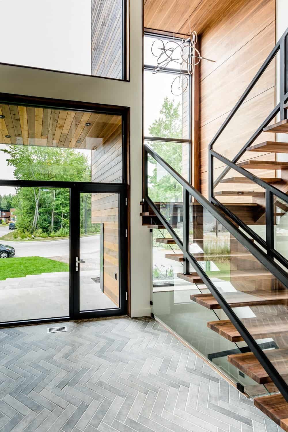 现代住宅，设有门厅楼梯，硬木台阶和玻璃栏杆。