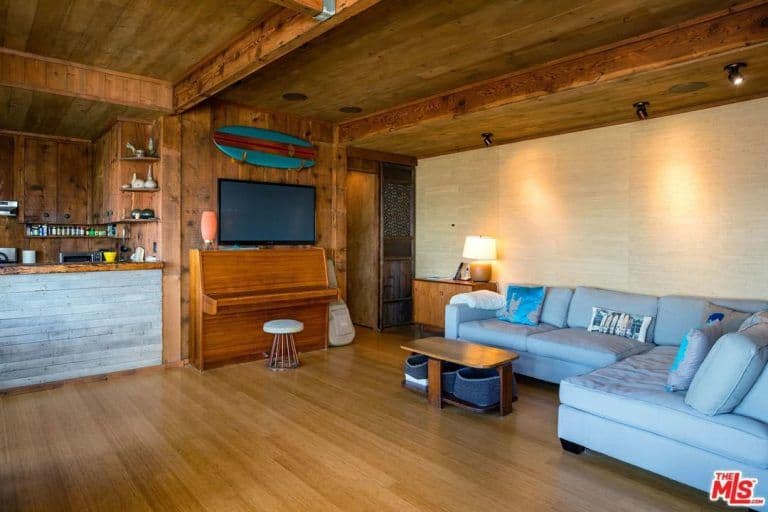 全木起居室和一个l形截面和电视上面安装木制的桌子配圆凳子上。