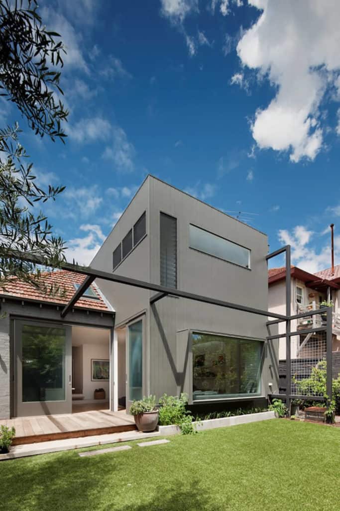 这座现代化的房子有一个灰色的外观，有一个维护良好的草坪区域。
