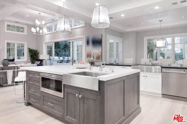 厨房设有一个大的中央岛台和明亮的天花板灯，以及光滑的白色台面。