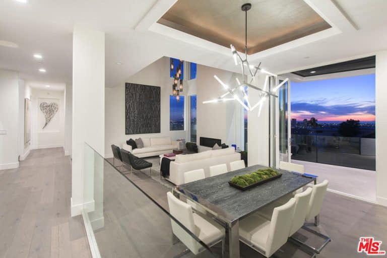 用餐和起居空间展示了美丽的白墙和优雅的地板，以及俯瞰洛杉矶城市的玻璃窗。