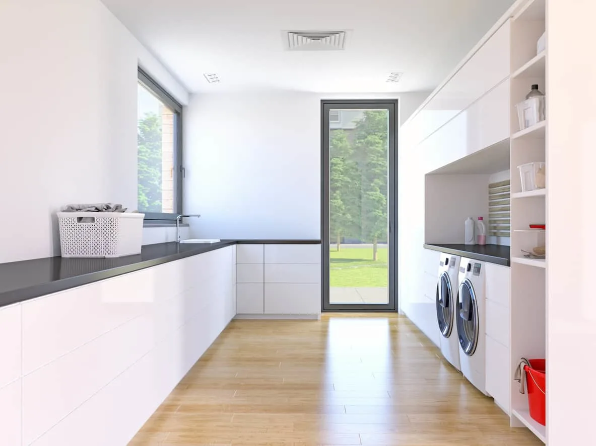 白色和暗灰色现代洗衣房功能广泛的存储空间,木地板,前置式洗衣机和烘干机,大量的自然光线从侧窗和后门。