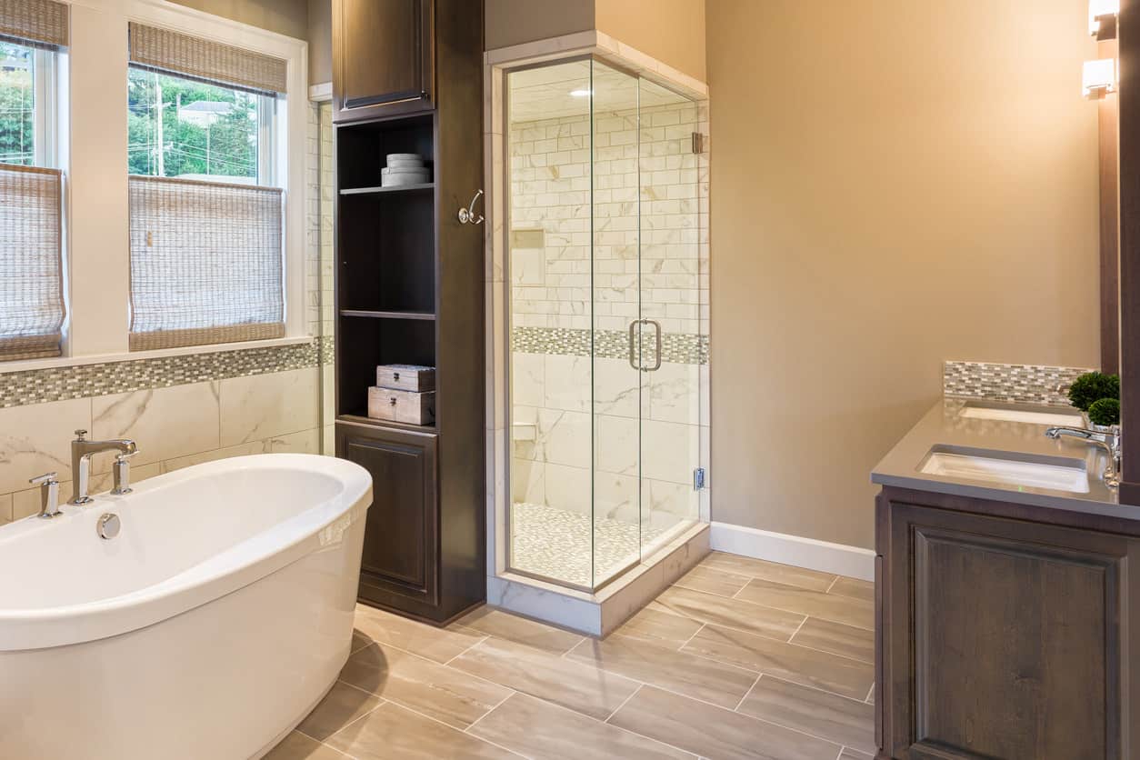 宽敞的棕褐色和白色主浴室与深色木质梳妆台。我喜欢步入式淋浴间旁边的内置木架子，它在独立的浸泡浴缸触手可及的地方。
