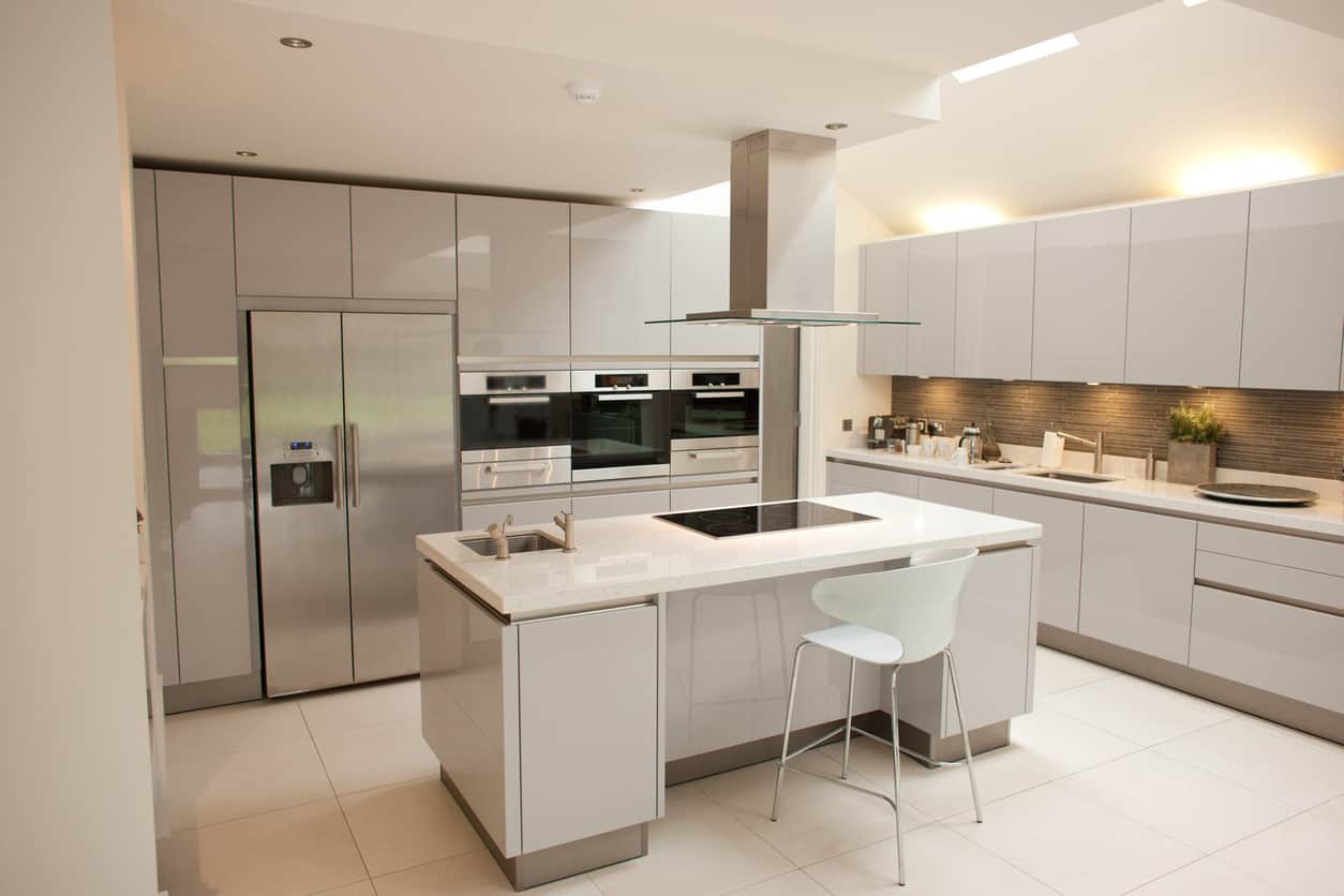 宽敞的全白色厨房，光滑的橱柜和白色的瓷砖地板。坦白地说，我一点也不喜欢这个厨房设计，但它是现代设计的一个很好的例子。