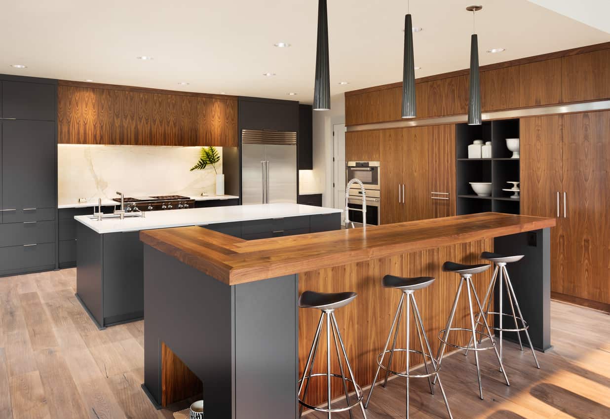 这个天然木材和深灰色的厨房散发着现代风格，但没有一些散发出的无菌效果。两个岛的豪华厨房提供了大量的橱柜空间(从地板到天花板)和两个岛的表面工作空间。
