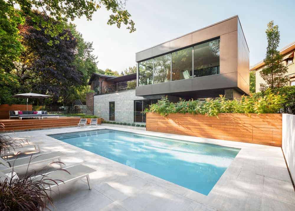 一个现代的灰色外观的房子，设有一个舒适的室外区域，游泳池和多个休息室。