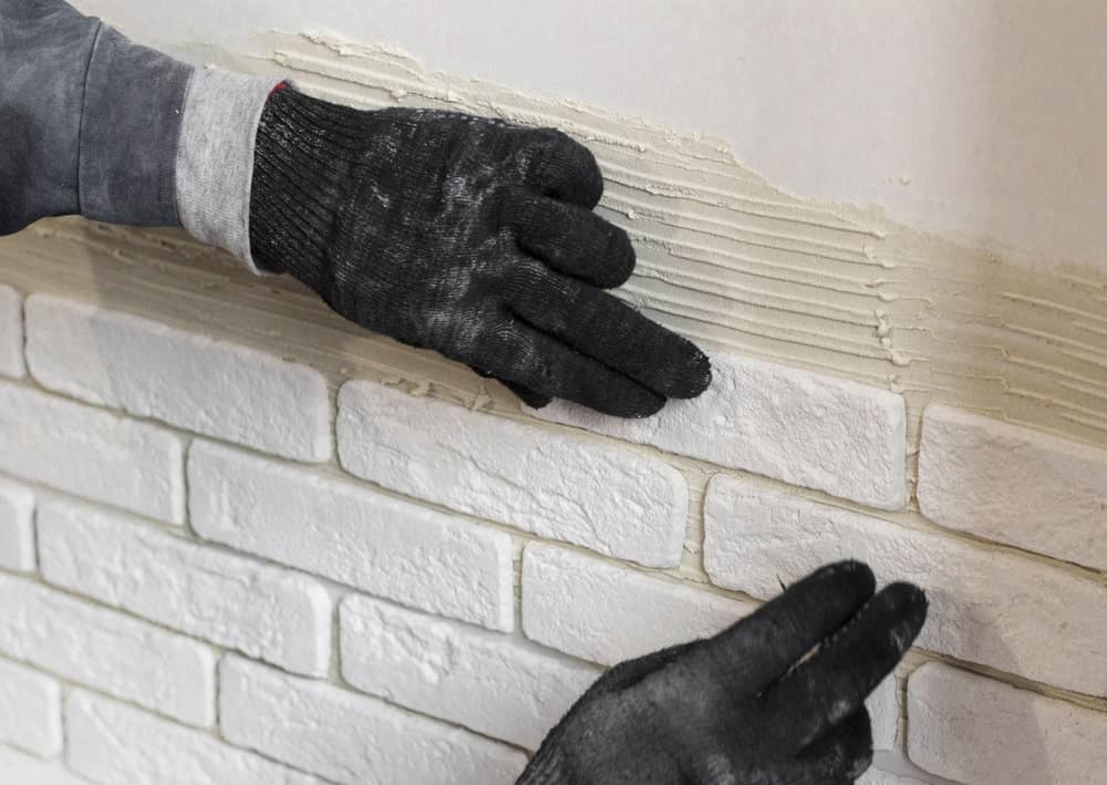 一双戴着黑色安全手套的手触摸着装饰性的墙壁。