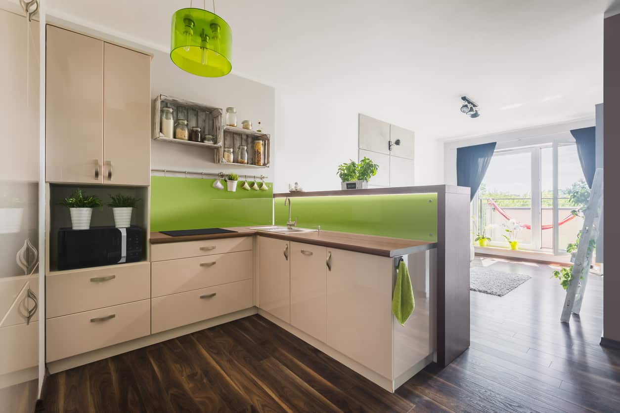 现代小厨房，深色木地板，绿色后挡板，白色橱柜和白色天花板。