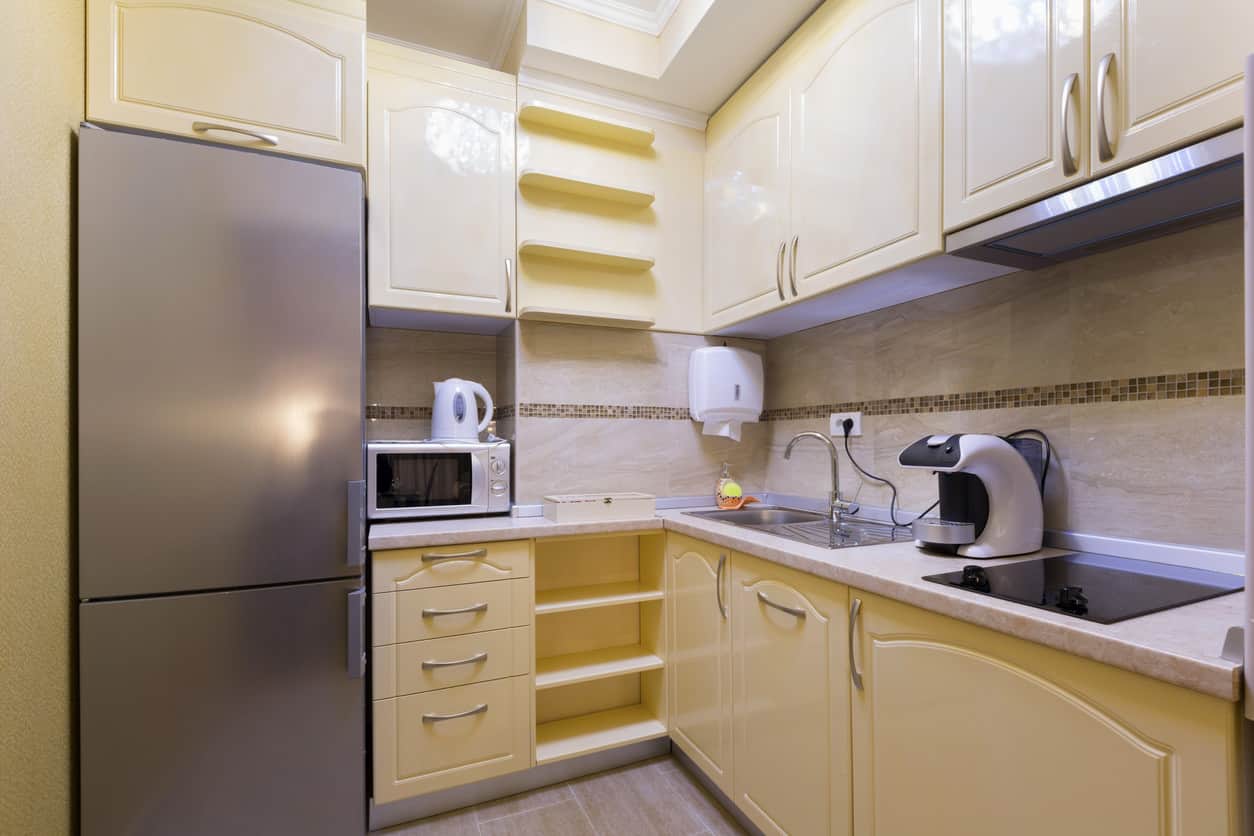 黄色的小厨房里有很多柜子。额外的光从天窗发射。我不喜欢米色的后挡板，应该是白色的。