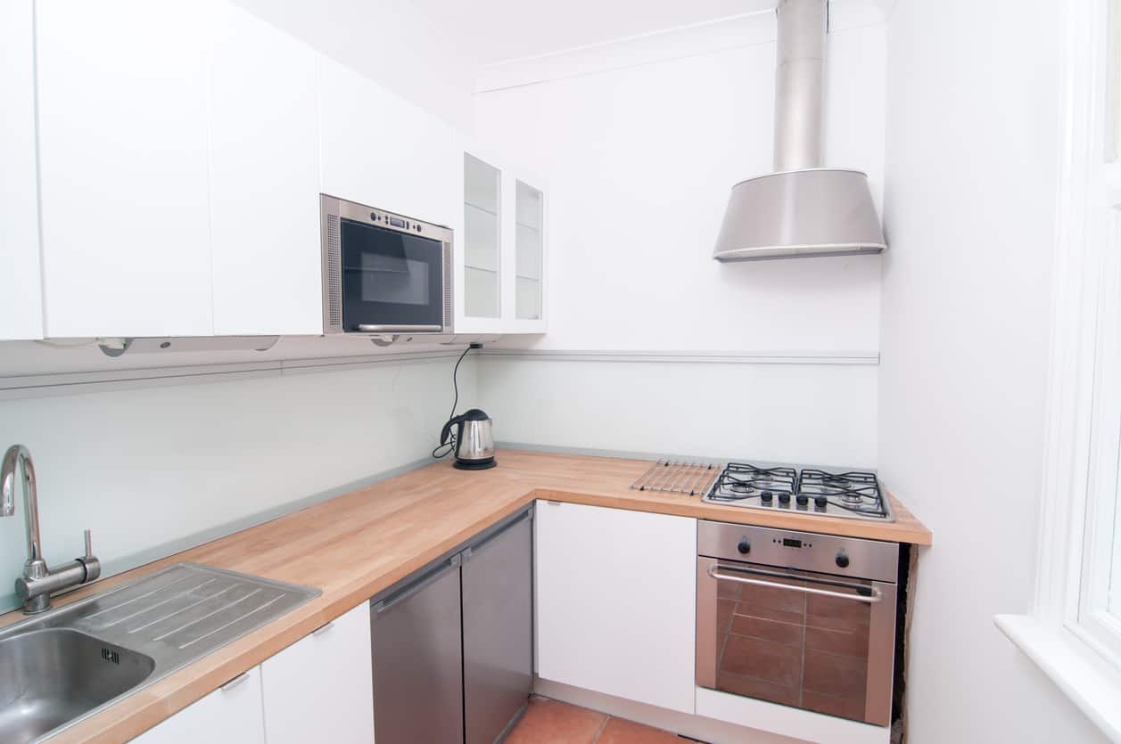 舒适的白色厨房，带木质台面和不锈钢电器。这有你需要的一切，包括一个相当大的柜台空间为这么小的厨房区域。