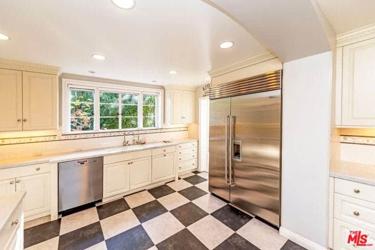 厨房的另一个特点是格子瓷砖地板、嵌入式灯、白色橱柜和不锈钢电器。