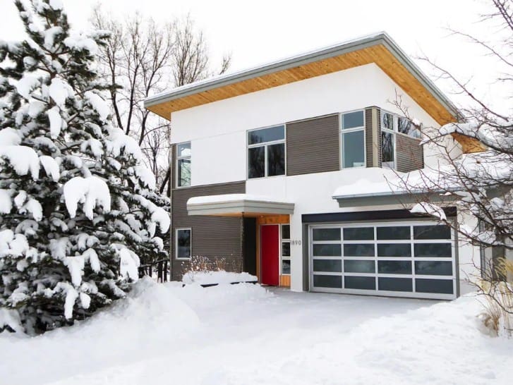 一栋现代的房子，外面是灰色的，被雪覆盖着。