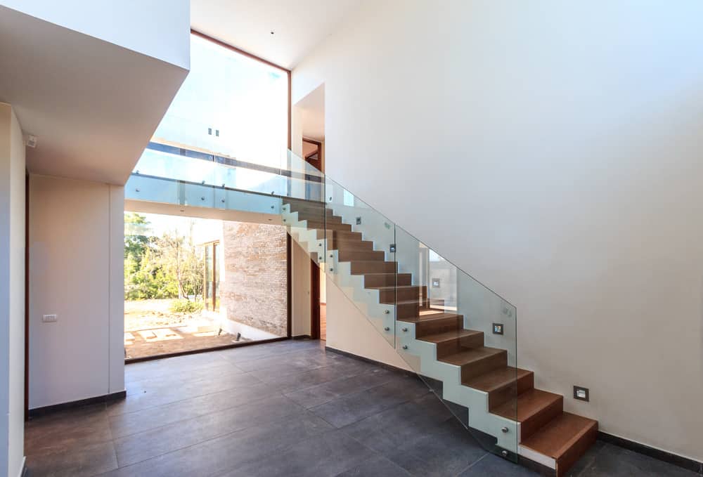 这个门厅以硬木地板和白墙为特色。楼梯上有漂亮的玻璃栏杆台阶。