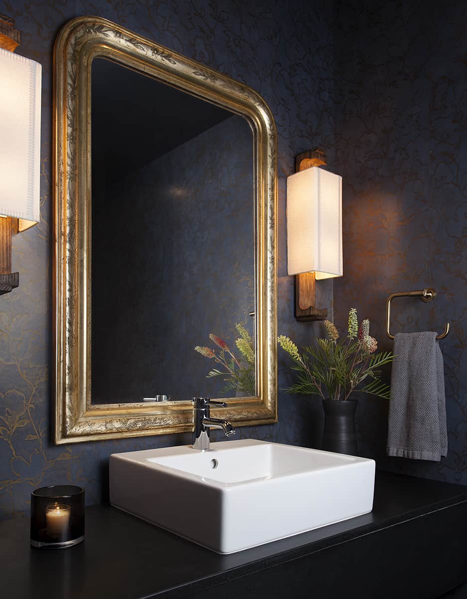 漂亮的化妆室，白色水槽，金色镜框镜子和德克萨斯州公寓的深色墙壁