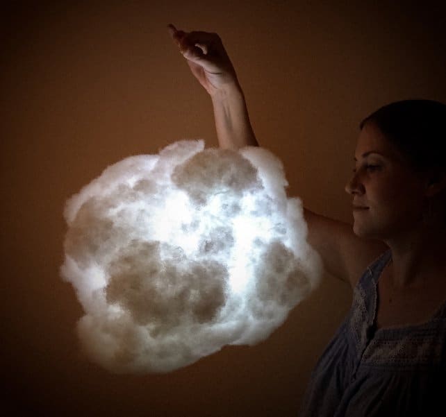 一位女士举着一盏点亮的云灯。