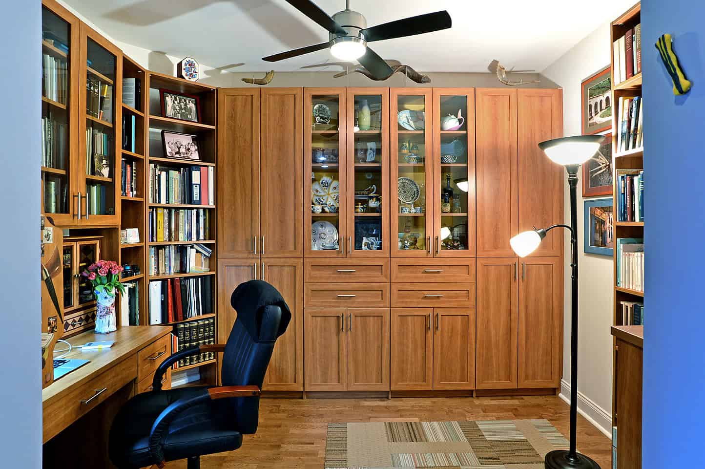 一个优雅的家庭办公室，有一张内置的桌子，与橱柜和书架有着相同的饰面。硬木地板反而与房间很相配。