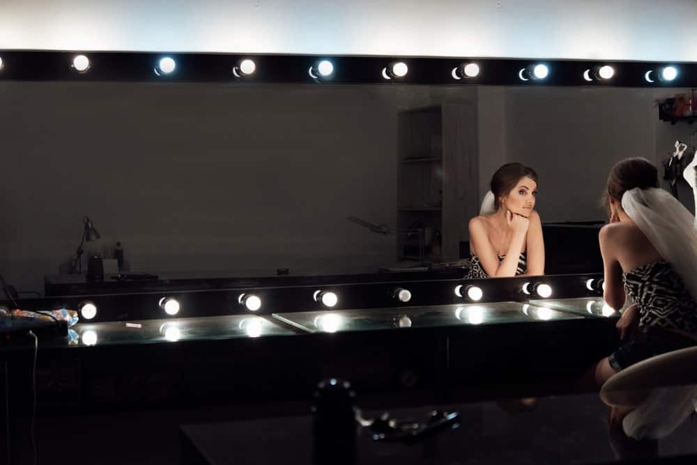 一位女士正对着一面亮着的镜子