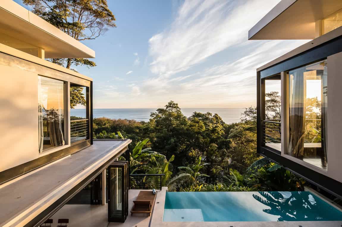 小无边泳池边缘的露台在山坡上的房子俯瞰丛林和太平洋。