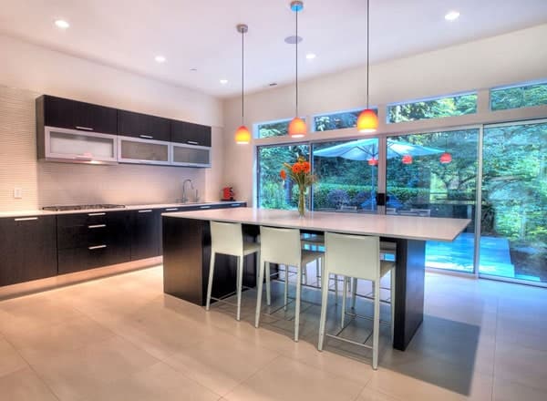 这个现代厨房配有迷人的浅色硬木地板和黑白相间的厨房岛台，也可作为早餐吧，配有白色凳子，顶部配有吊灯。