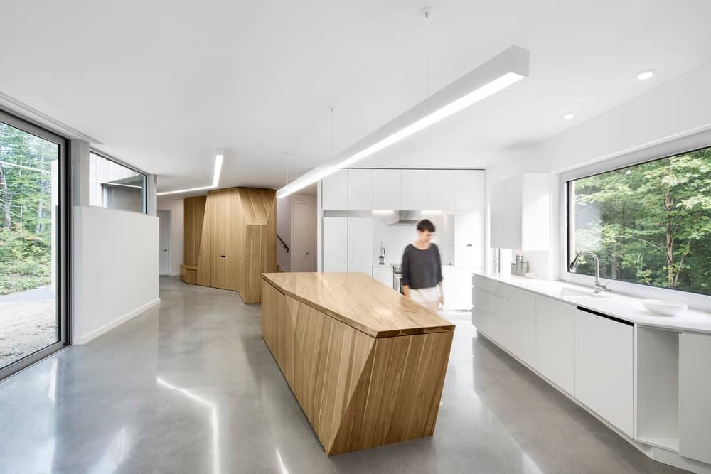 极简主义的现代厨房，在狭窄的房子里有天然木材和白色橱柜