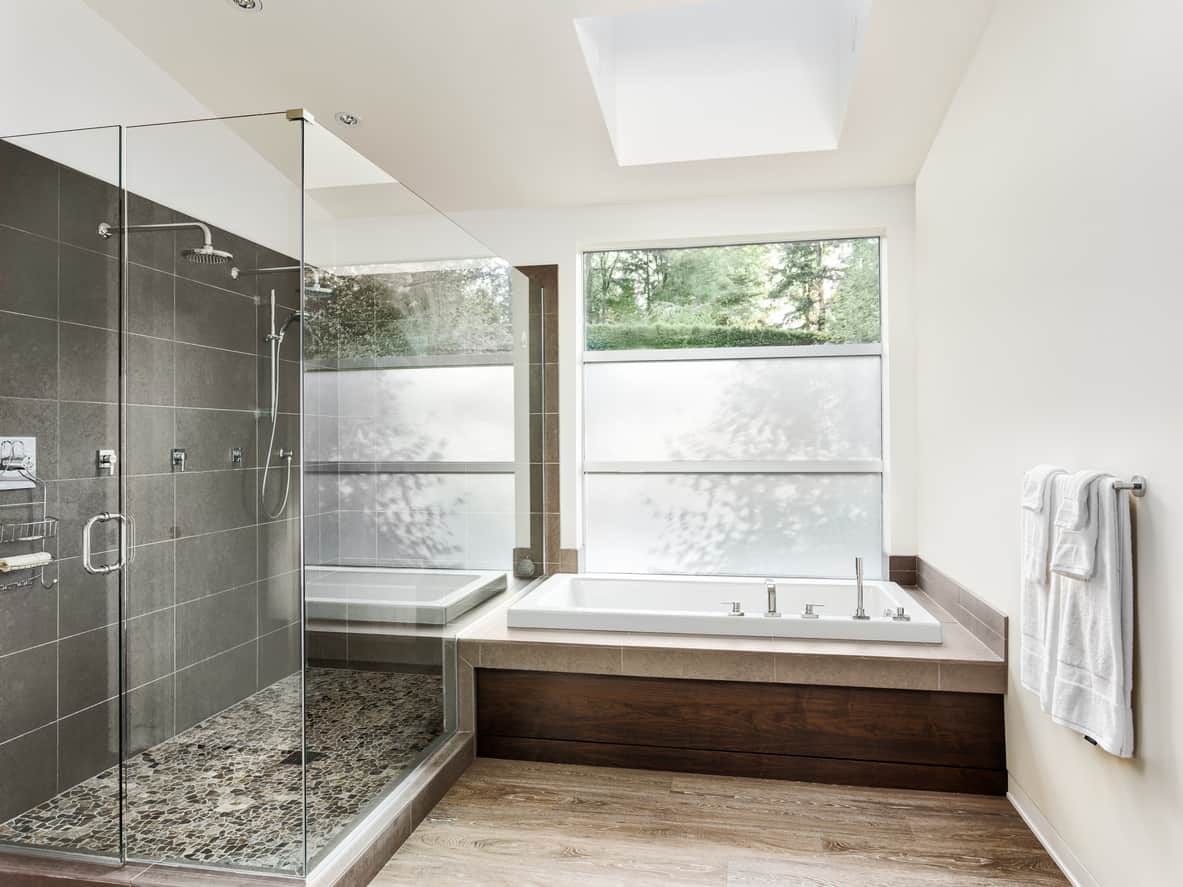 这是一个翻新的主浴室，是灰色、棕色和白色的。我喜欢这个天窗和灰色的淋浴配色。我不太喜欢棕色，但布局真的很棒。