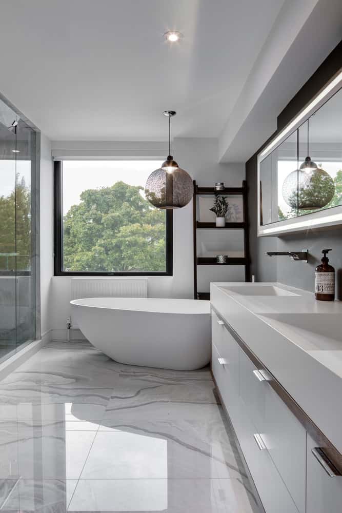 主浴室带有托盘状的水槽，配有现代白色梳妆台，旁边是白色独立式浴缸，对面是玻璃步入式淋浴间。