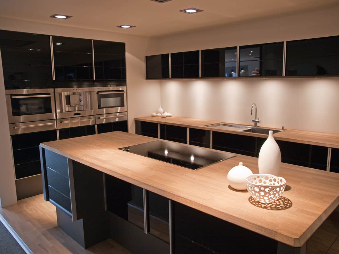 黑色的厨房橱柜与浅色的木岛台和台面融合在一起。这是一个奇妙的配色方案，创造了一个美丽而富有戏剧性的厨房。地板和台面很相配。