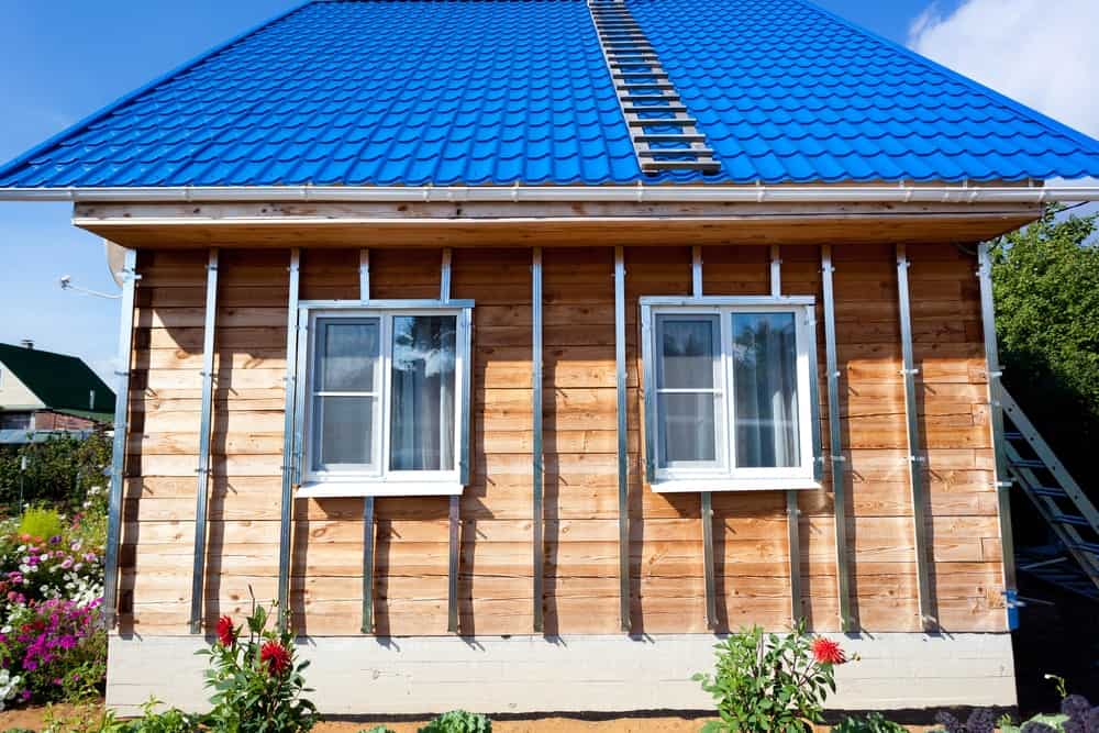 有蓝色屋顶和木板和板条壁板的房子。