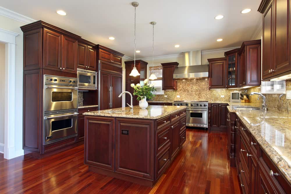 深红宝石红色的豪华木质厨柜和红色木地板给这个厨房一个红色的配色方案。我喜欢地面色调的后挡板和花岗岩台面;它与厨房的木质色调很相配。