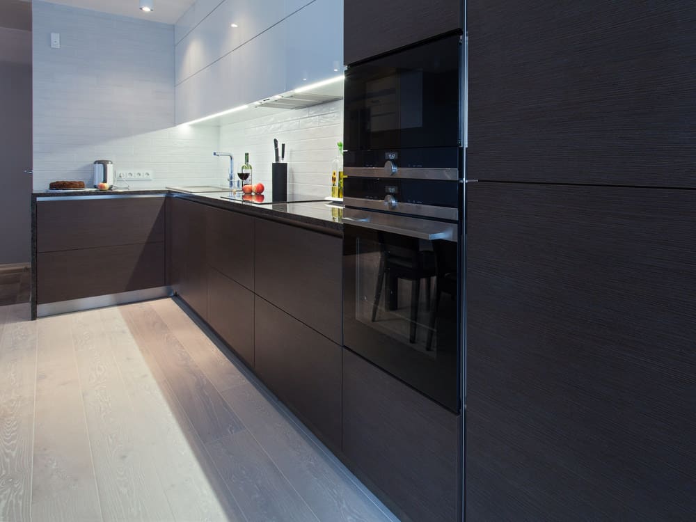 极简主义的l形黑色厨房，上面有一些白色橱柜。