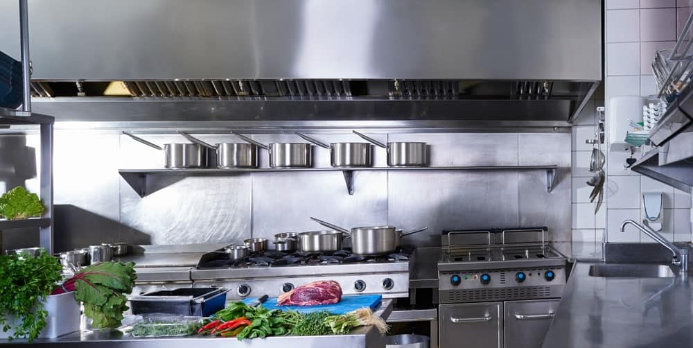 专业的不锈钢厨房，锅陈列在烹饪区上方的单一窗台上。
